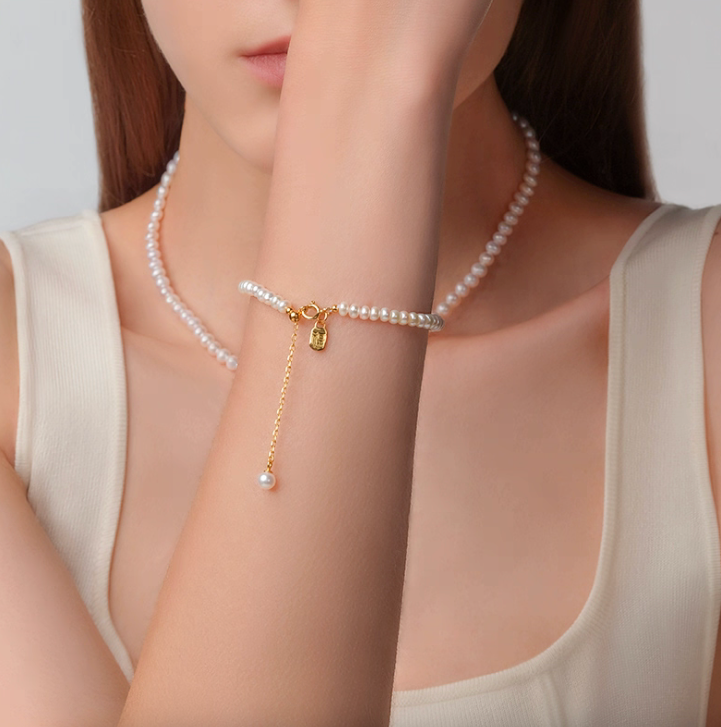 Styling shot of gold-plated Fu tag pearl bracelet paired with a pearl necklace, classic minimal jewelry look.