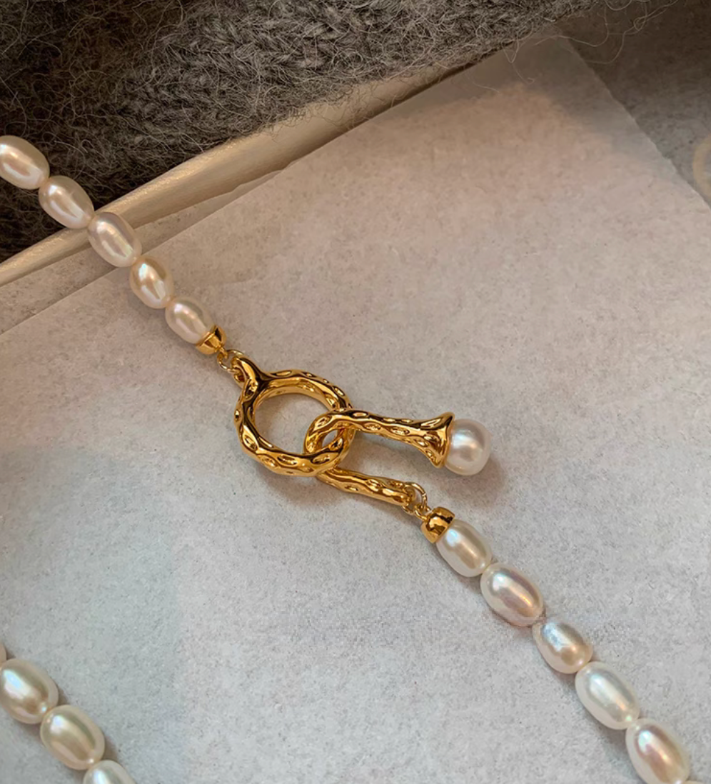 Close-up of gold clasp detail on freshwater pearl necklace with natural oval pearls and refined finish