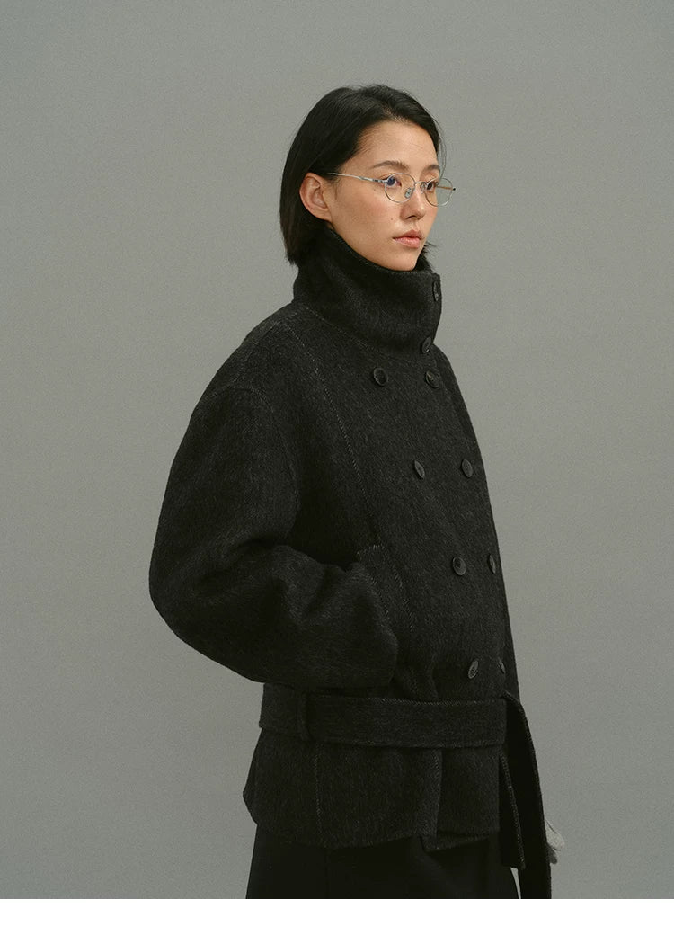 Side view of charcoal funnel-collar coat buttoned to the chin with belt