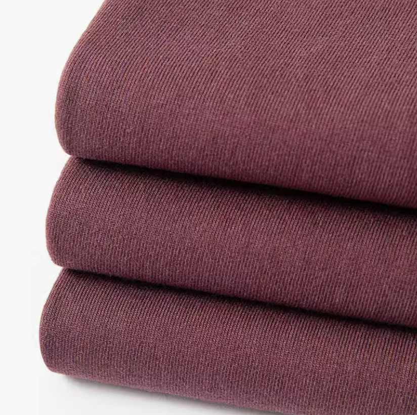 Grape Glow Tee Burgundy folded fabric stack showing soft cotton texture