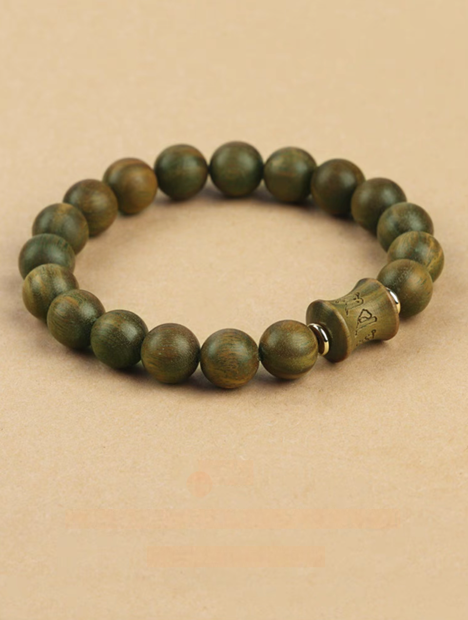 green sandalwood beaded bracelet shown at angled view emphasizing carved centerpiece and natural wood grain texture
