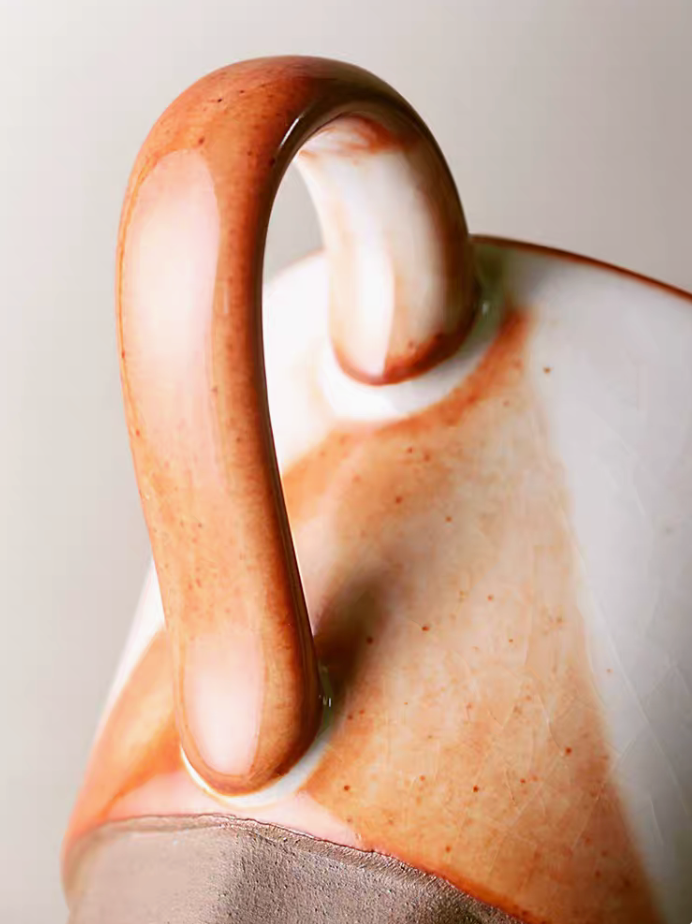 Close-up of Style 1 ceramic mug handle showing glossy off-white and orange glaze transition and handcrafted texture