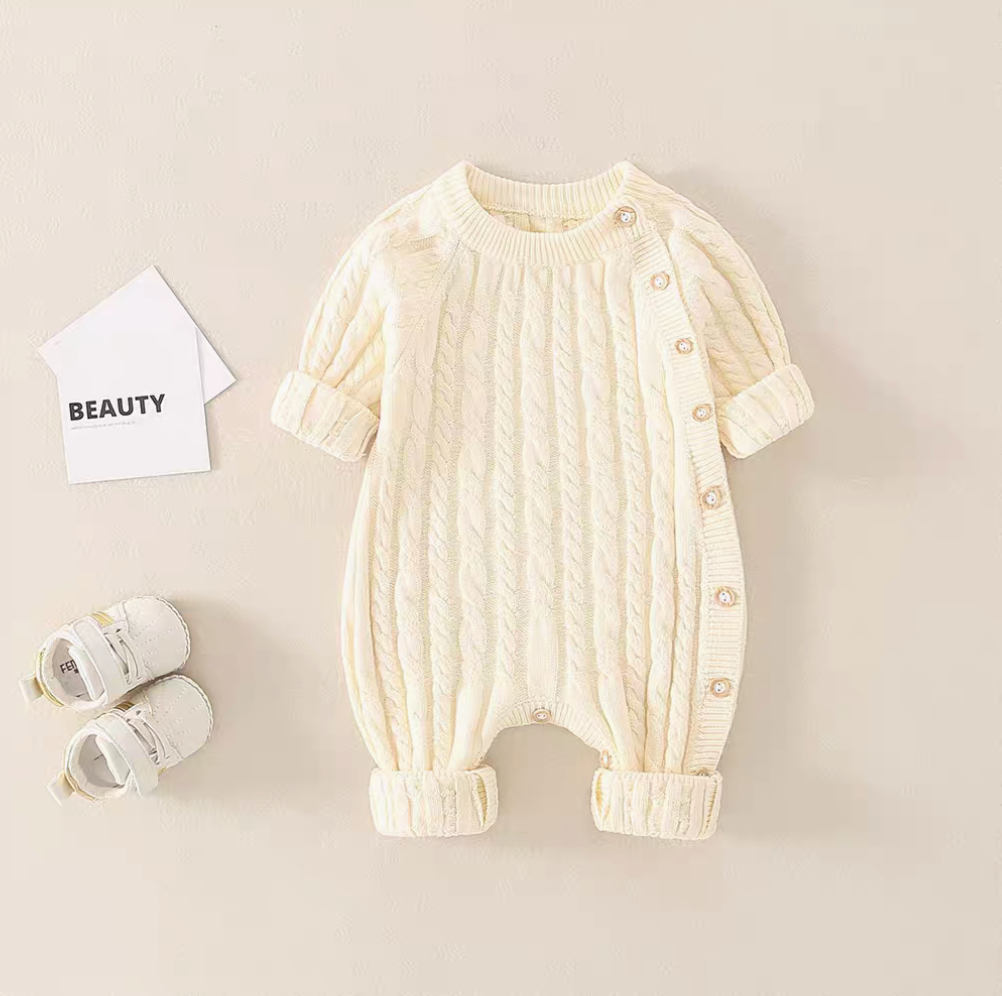White cable knit baby romper front view with side button closure and ribbed cuffs