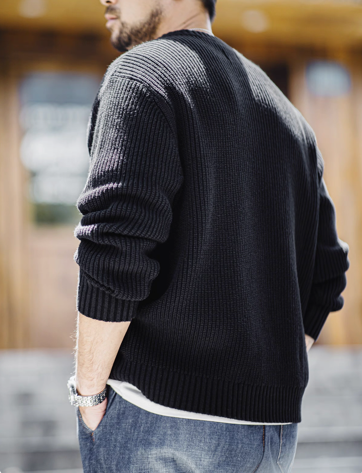 Back view of man wearing black Henley knit sweater in sunlight.