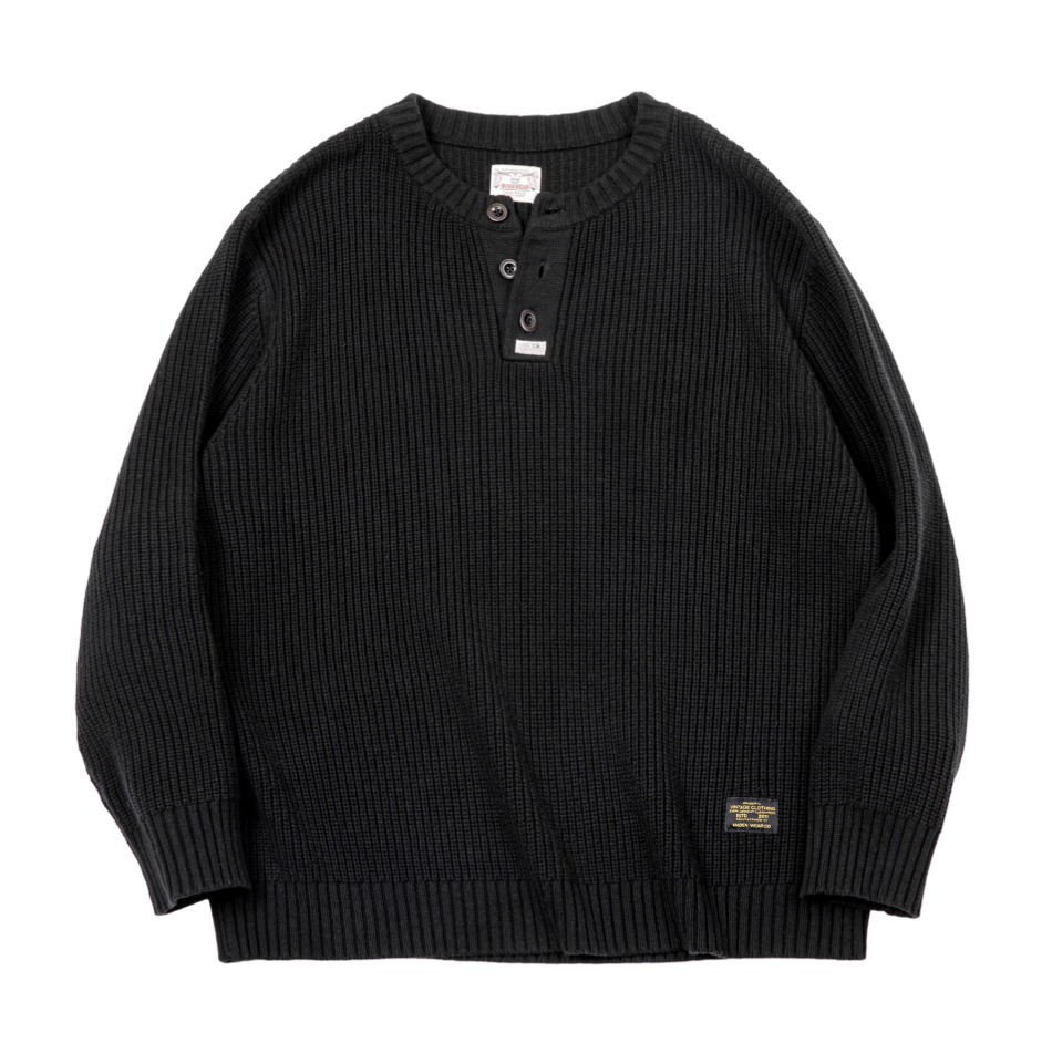 Flatlay of black ribbed Henley knit sweater with button neckline.
