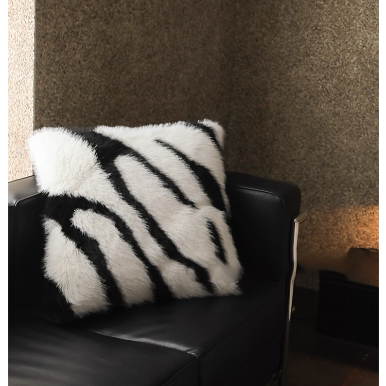 White and black zebra faux fur decorative pillow on black leather sofa