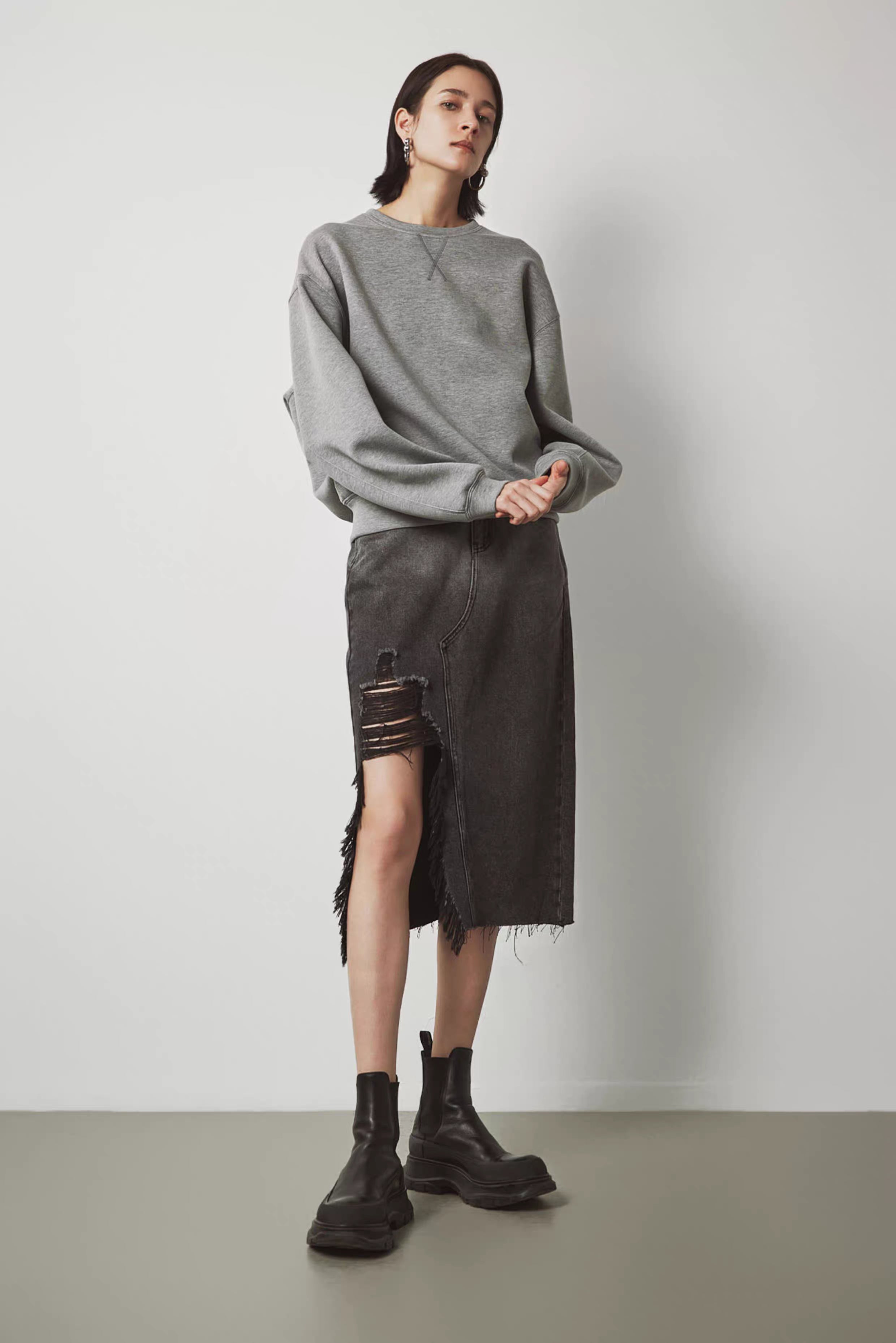 Women’s gray oversized sweatshirt paired with distressed black denim skirt
