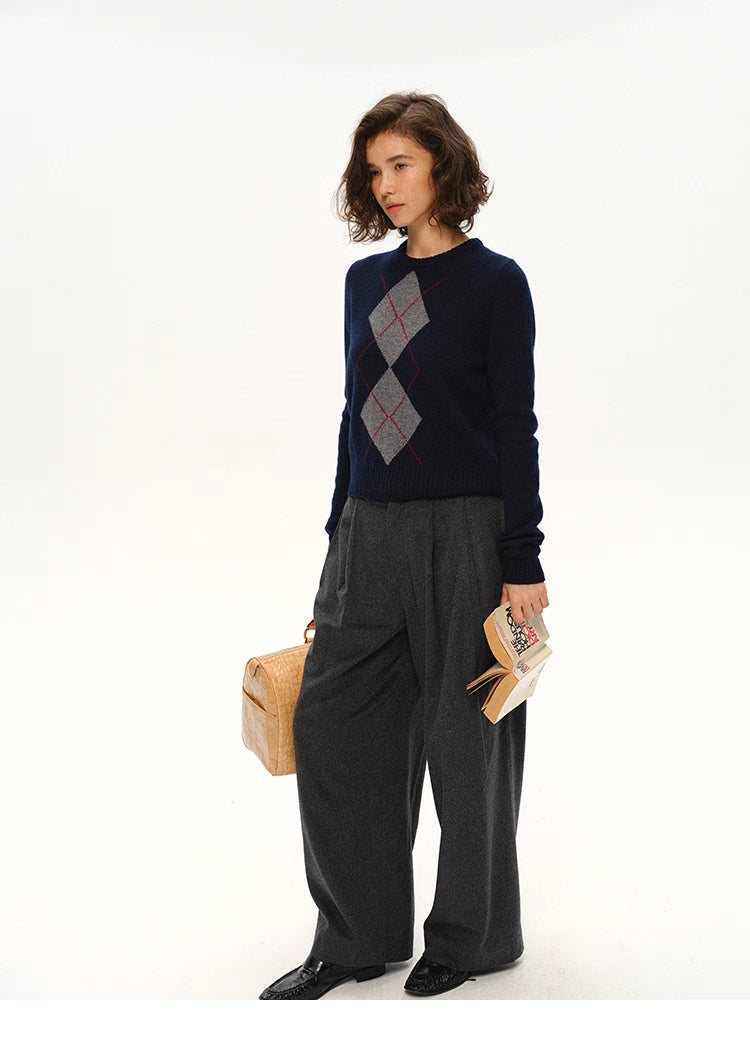 Full body shot of navy argyle wool sweater styled with gray wide-leg pants and a woven tote bag.