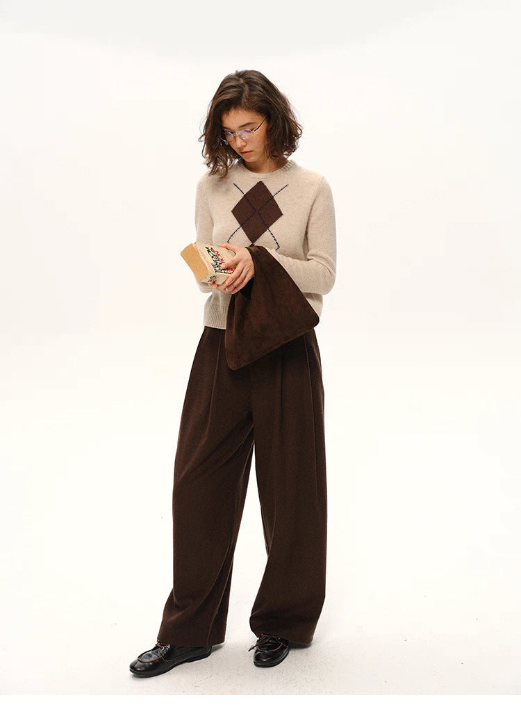 Full body shot of beige argyle wool sweater styled with brown trousers and matching suede bag.