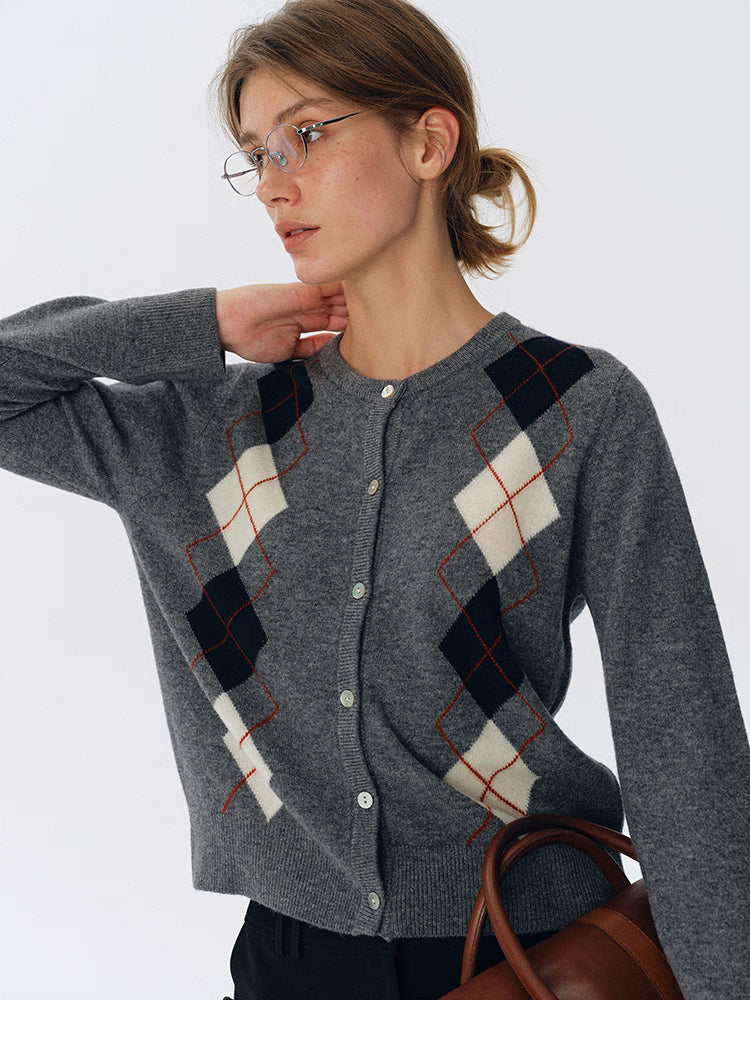 Close-up of charcoal gray argyle wool cardigan showing ivory and navy diamonds with fine red lines.