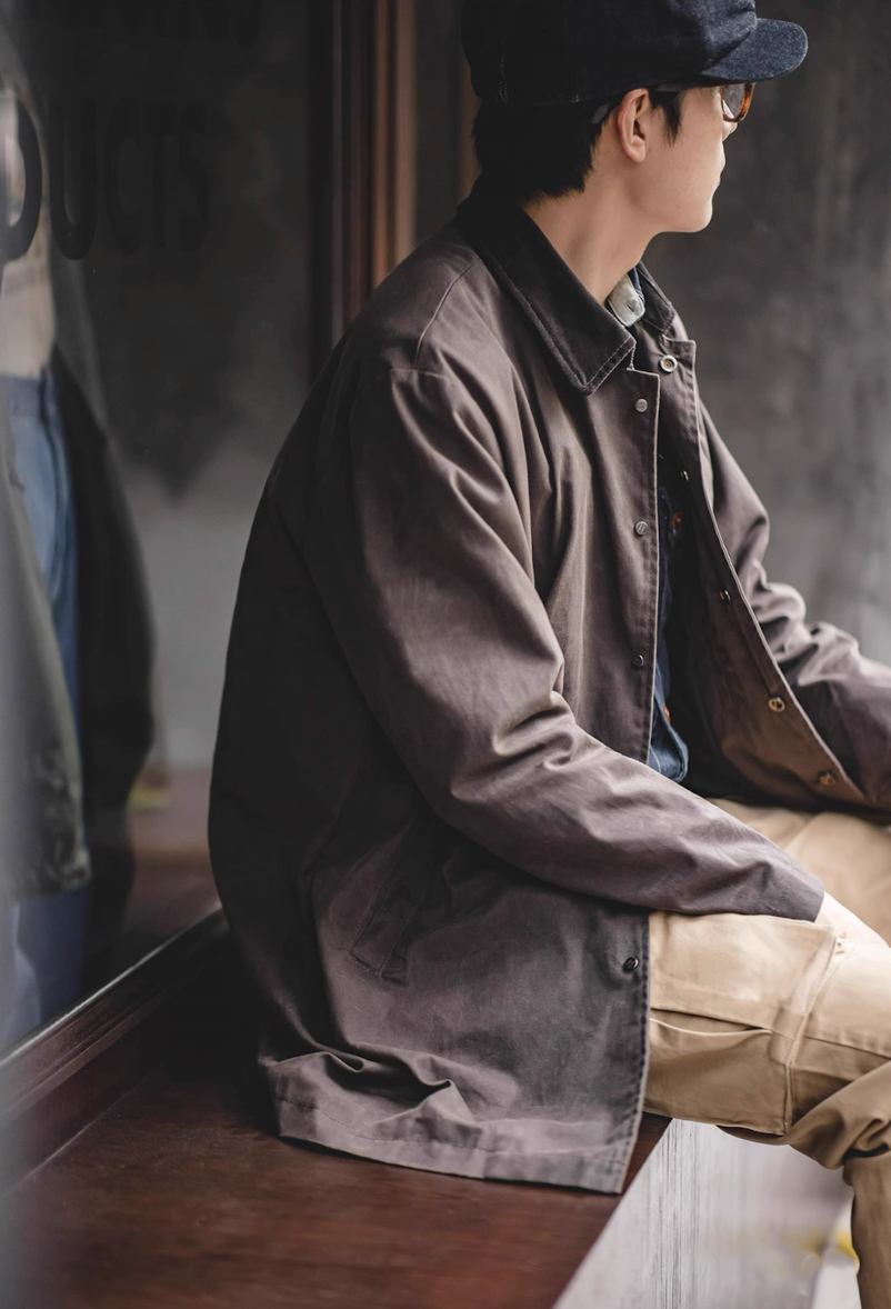 Side view of model wearing vintage waxed cotton coat by window