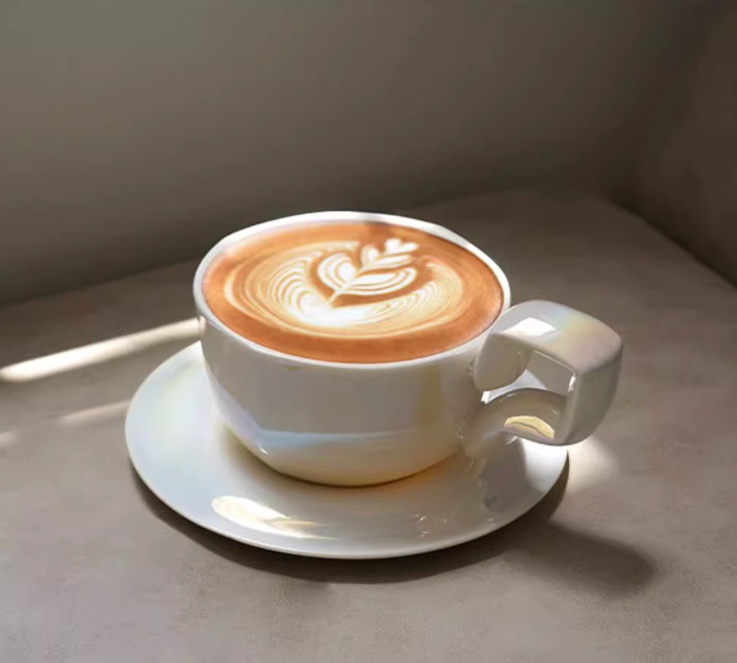 Pearlized Mother of Pearl White balloon-handle ceramic coffee mug with latte art, lifestyle usage on saucer