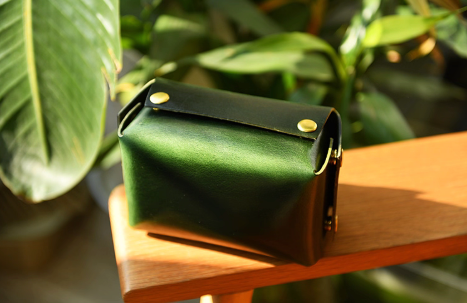 Rear view of olive green leather tissue box showing folded leather flap and brass snaps.