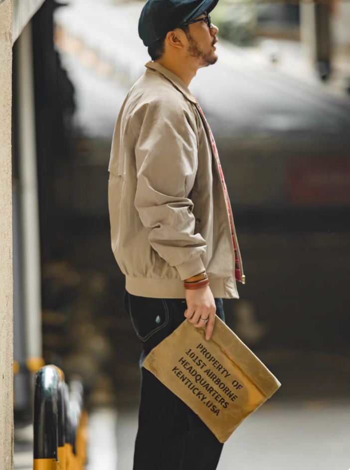 Side view of model wearing khaki Harrington jacket with tartan lining