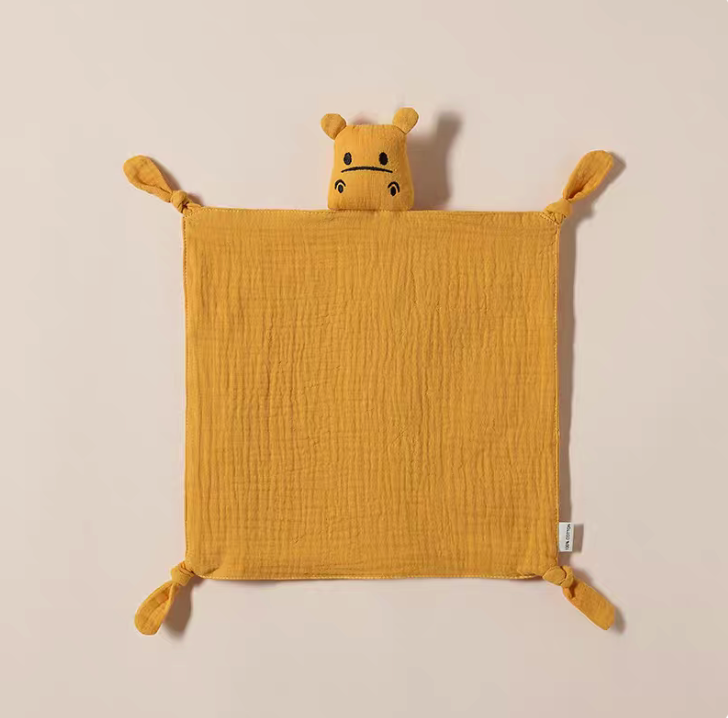 Yellow knotted corner muslin baby comfort cloth with plush animal head laid flat showing soft cotton texture