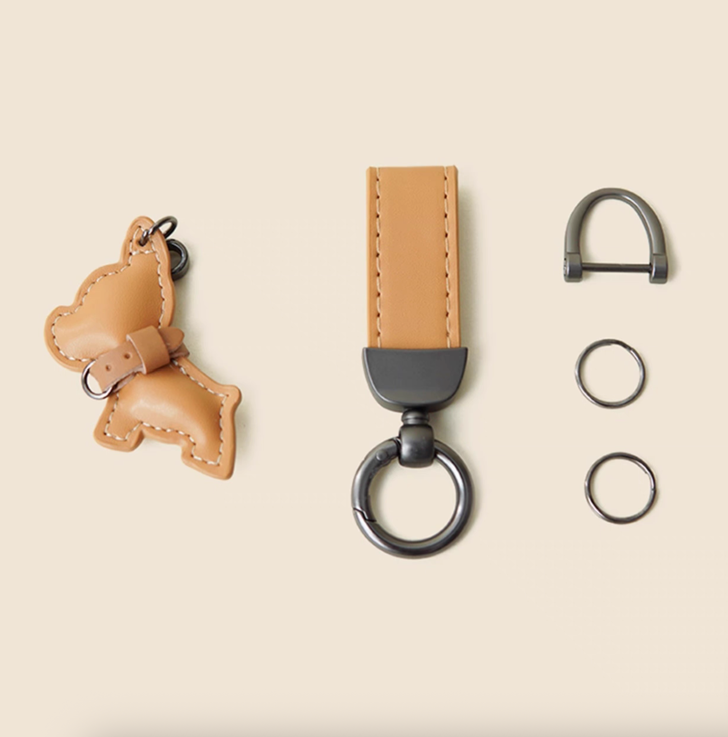 Disassembled view of puppy keychain showing PU charm, wrist strap, and metal rings.