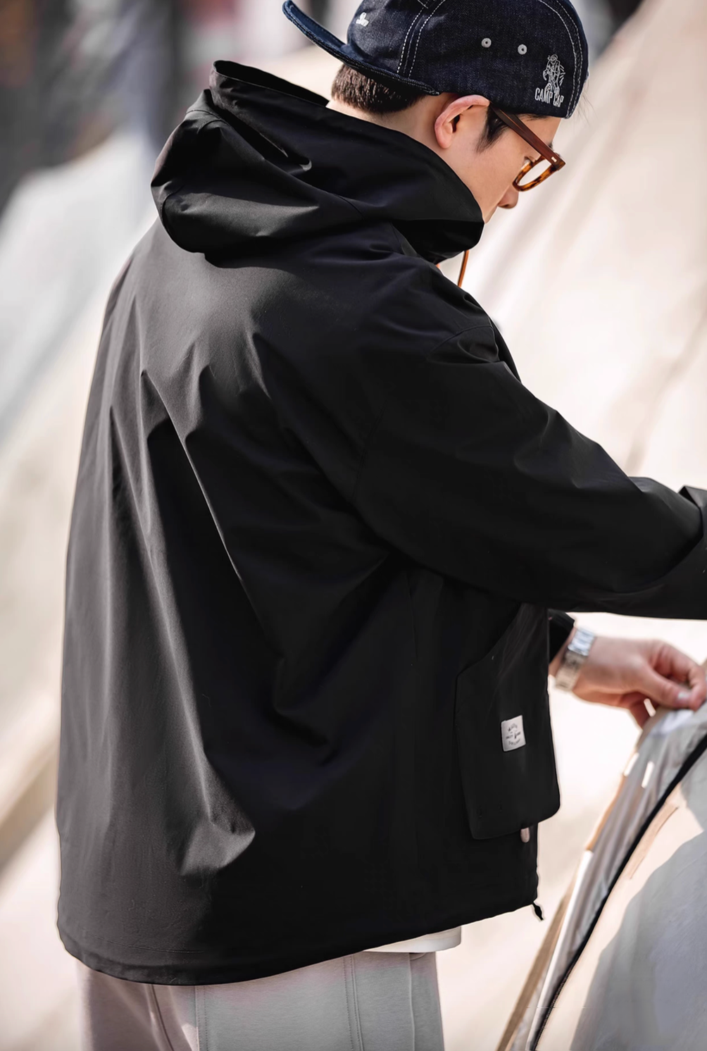 Back view of Charcoal Black Lightweight Hooded Anorak Jacket worn by model showing hood structure and smooth lightweight fabric