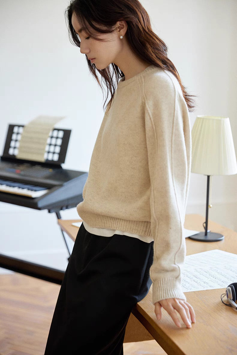 Mist white merino wool sweater shown in side profile near desk with soft studio lighting emphasizing refined texture