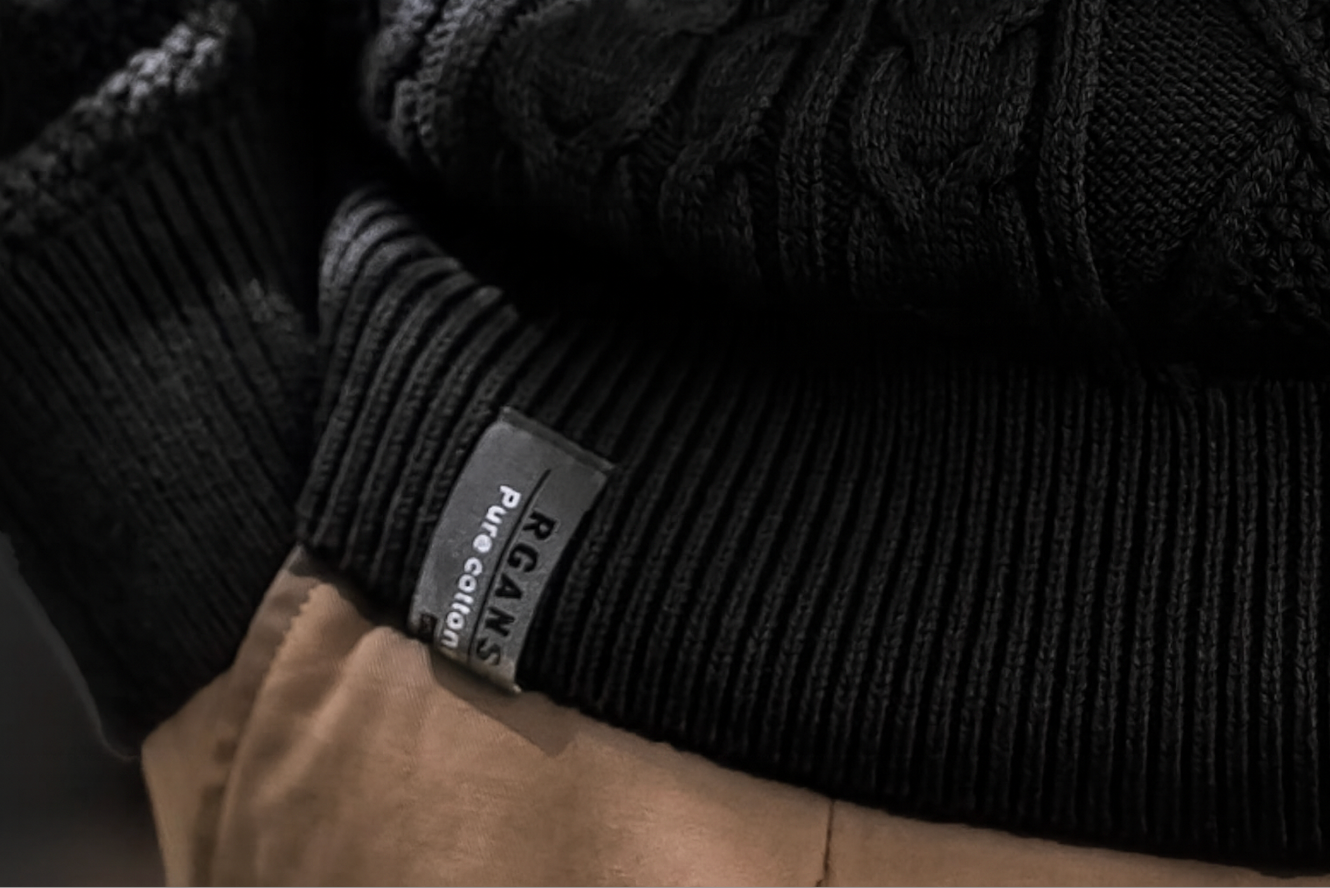 Ribbed hem with label, men’s cable knit black sweater.