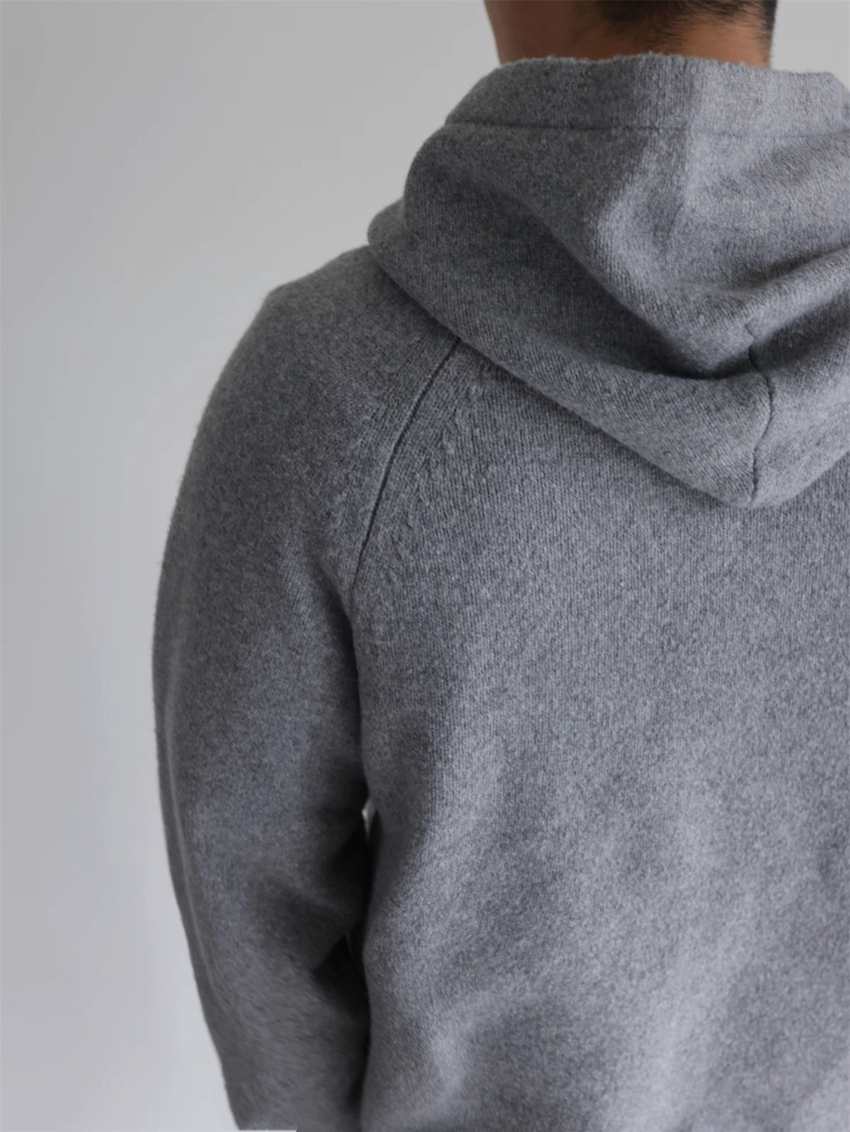 Back view of gray knit hoodie showing clean no-drawstring design