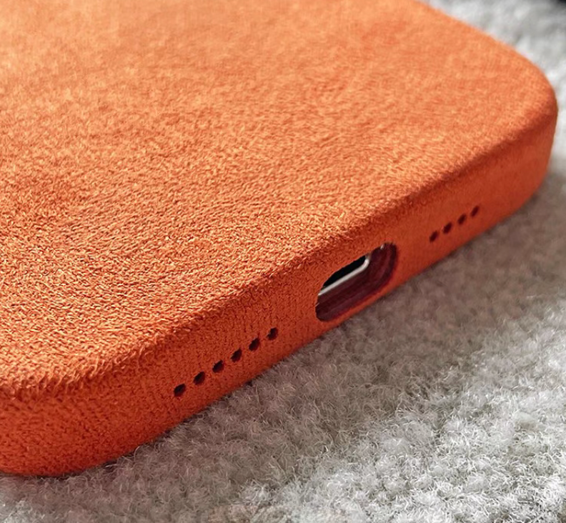 Orange microfiber suede phone case bottom view showing speaker holes and charging port