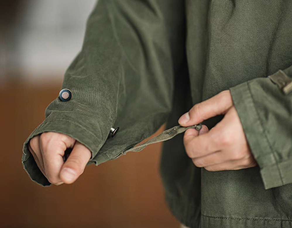 Close-up of Army Green military deck jacket hoodie sleeve, showing adjustable cuff strap and button detail