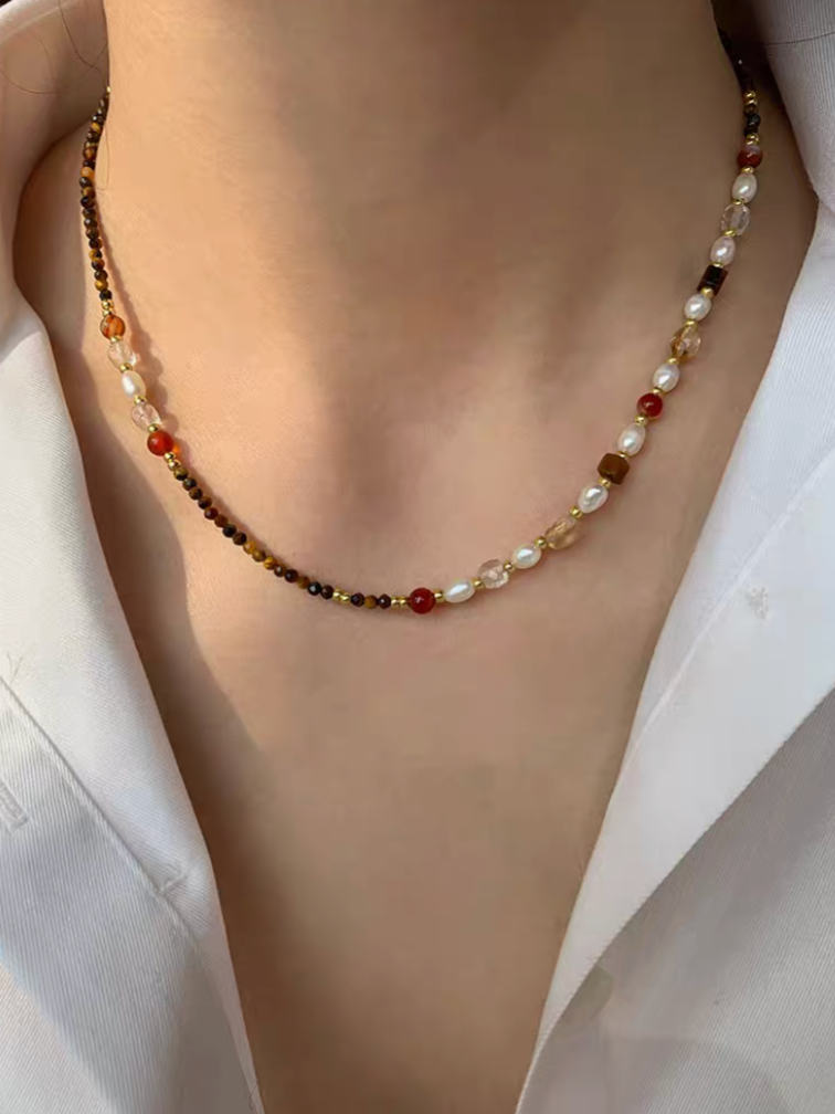 Close-up of multicolor beaded choker necklace with freshwater pearls, tiger eye beads, and gold accents worn on neck