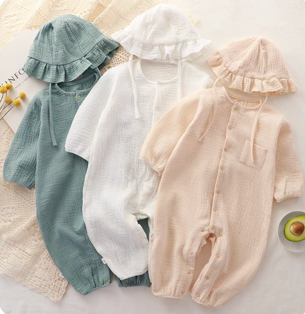 Assorted muslin long sleeve baby rompers with matching hats in multiple colors displayed flat lay