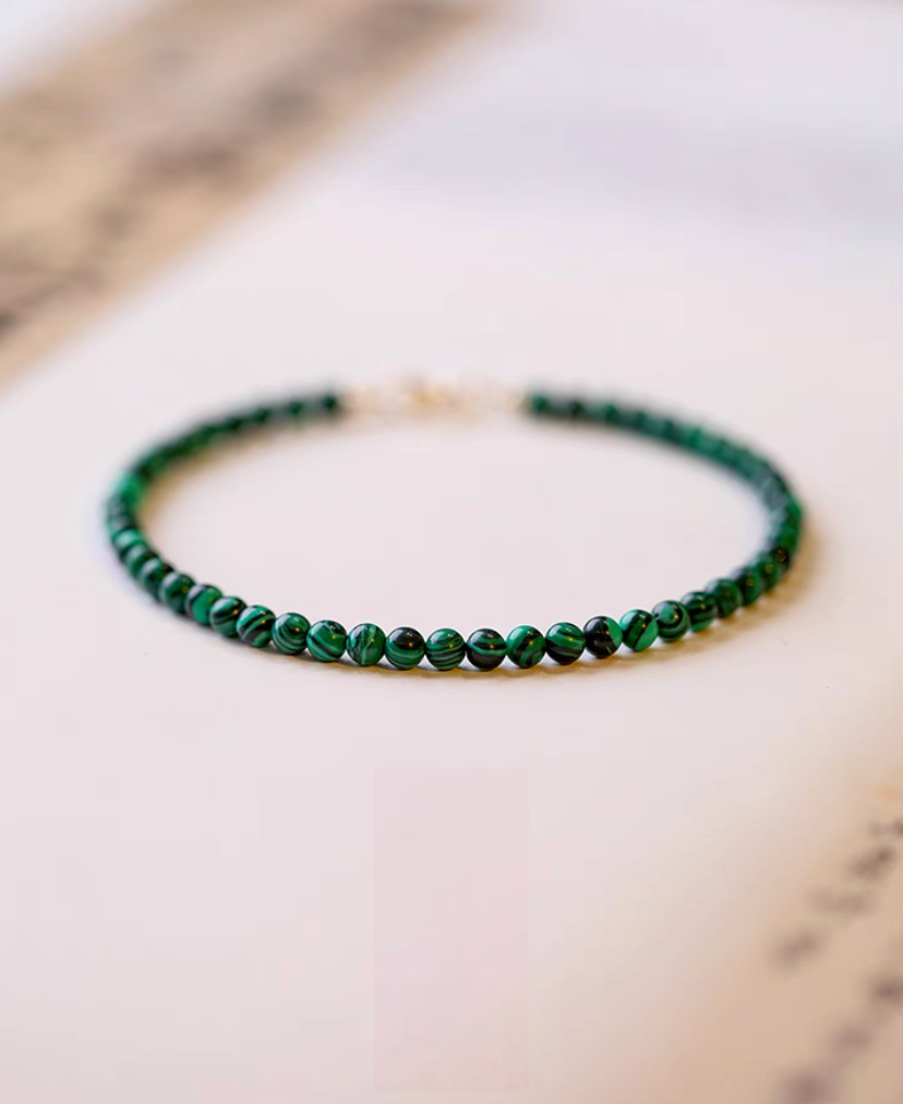Natural green malachite bracelet with polished round beads displayed in a minimal flat lay on a clean white surface