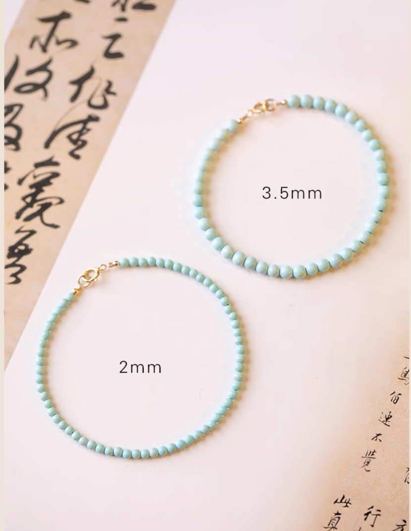 Two natural turquoise bracelets displayed flat showing 2mm and 3.5mm bead size comparison with gold clasps