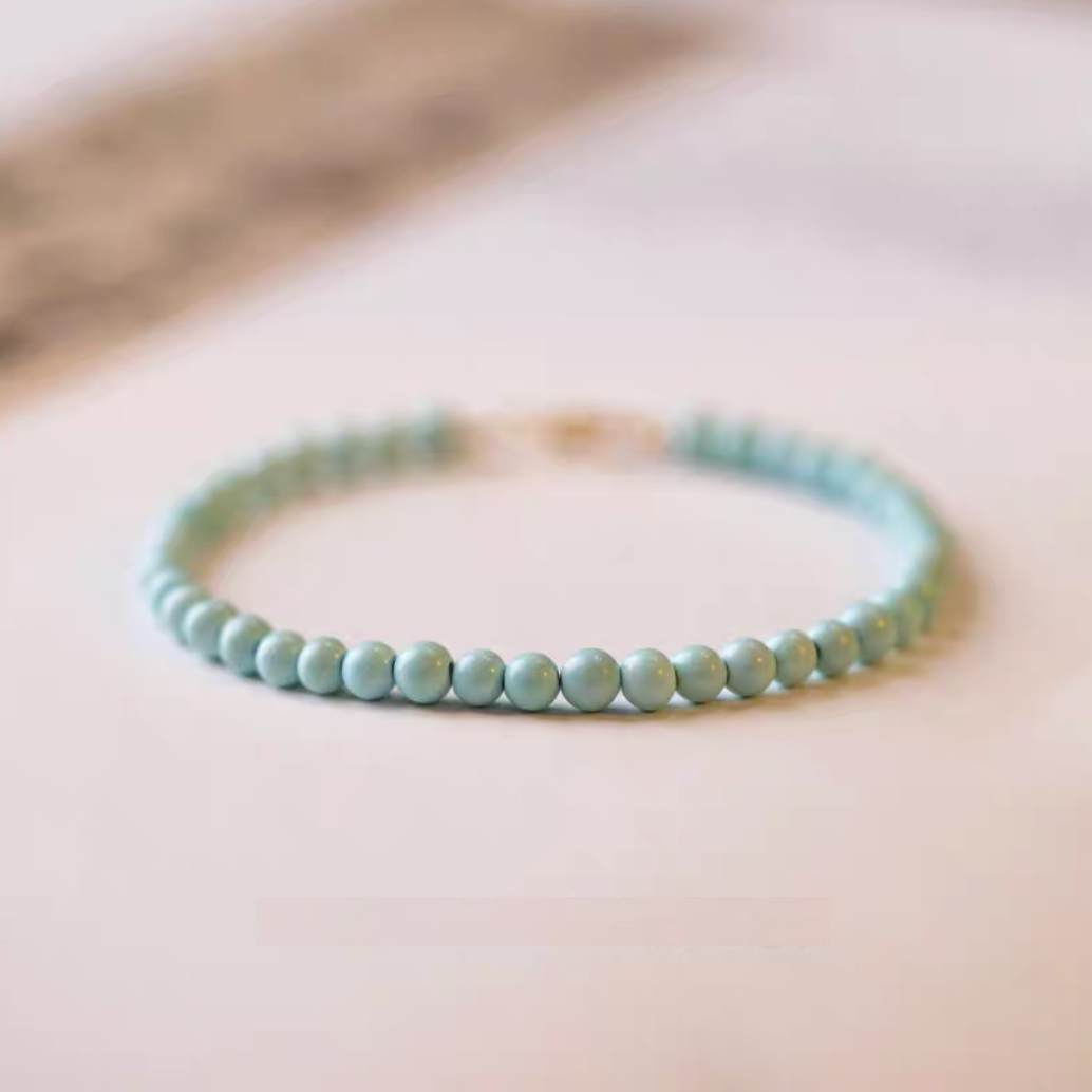 Natural turquoise bracelet with 3.5mm beads arranged in a circle on paper surface with minimal background