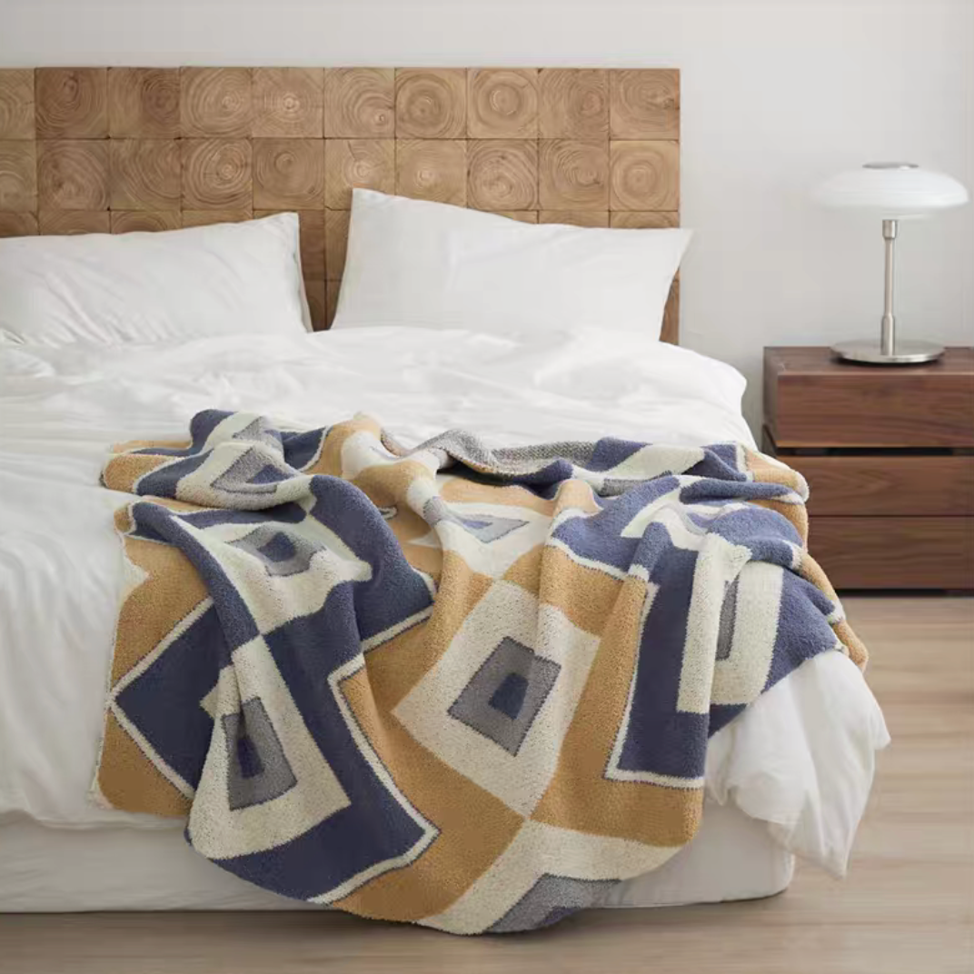 Layge chenille throw blanket with navy blue and beige geometric square pattern spread on bed