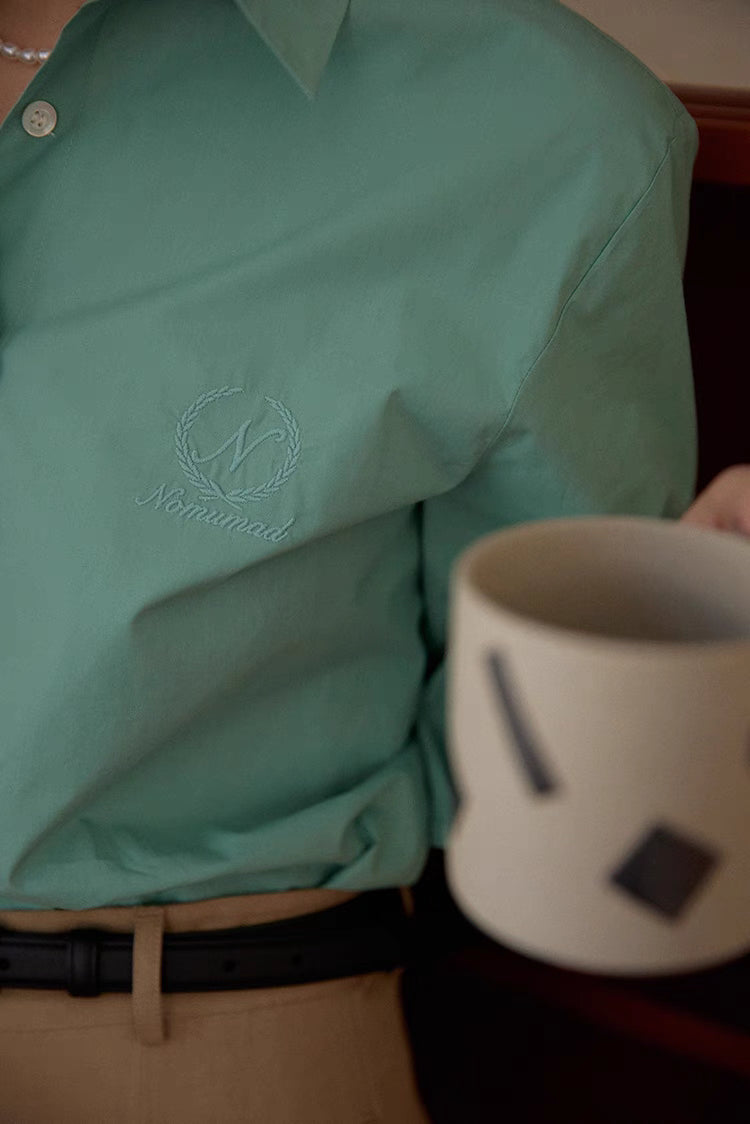 Green embroidered relaxed shirt close-up showing ivy monogram detail and smooth cotton texture