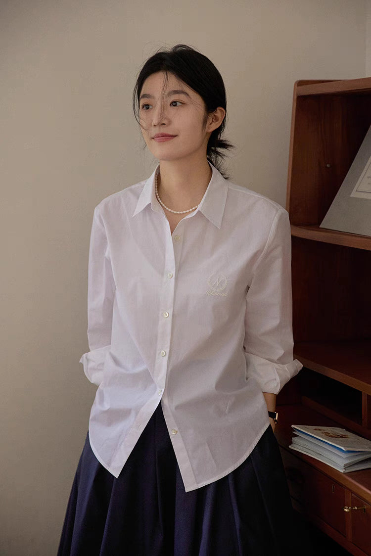 White embroidered relaxed shirt worn in soft indoor light paired with skirt for a refined classic look