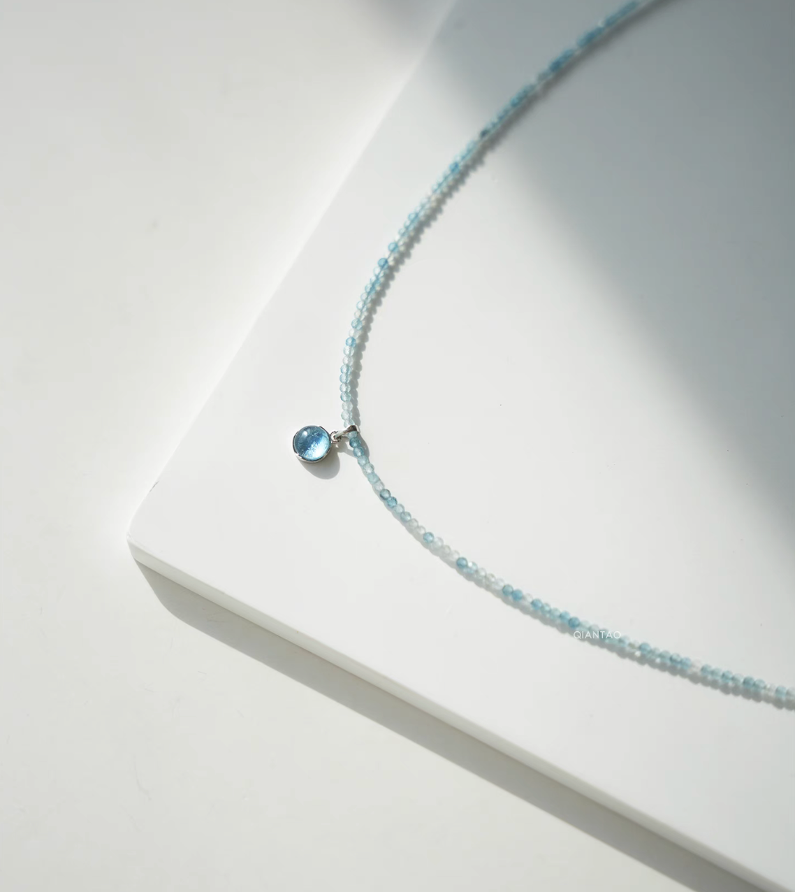 Close-up of Ocean Breeze aquamarine necklace featuring round aquamarine cabochon pendant on delicate blue beads