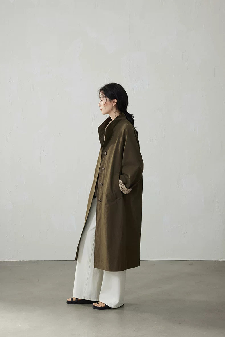 Side profile of an Olive longline cotton trench coat with stand collar and rolled paisley cuff