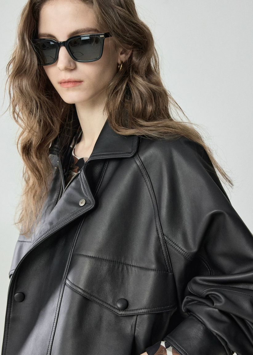 Close-up of leather point collar, snap tab and covered-snap flap pocket on black lambskin jacket