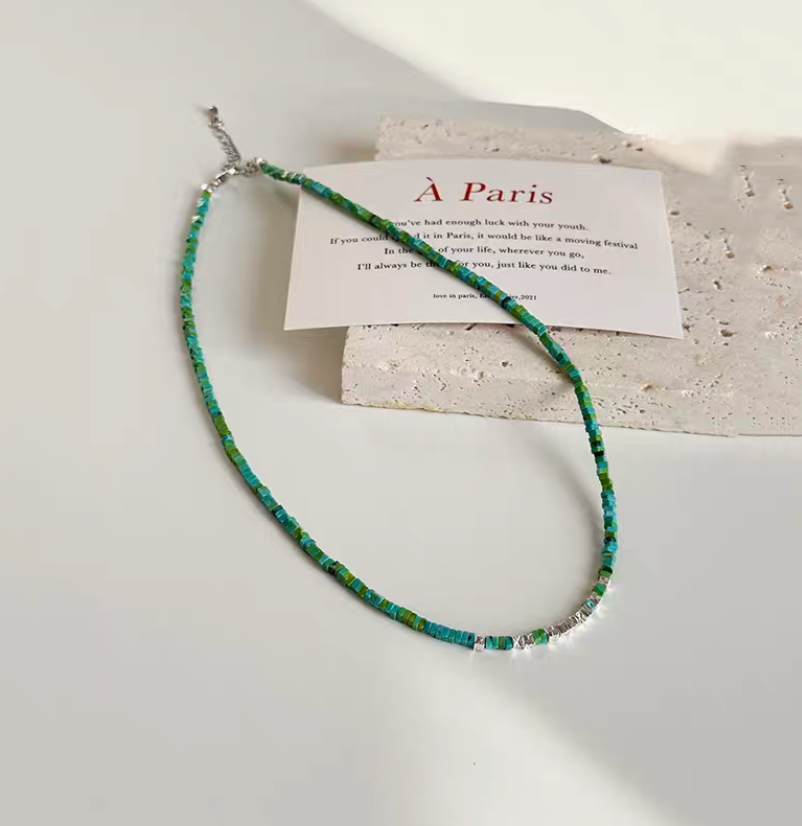 Parisian Charm Mosaic Necklace with turquoise beads and silver fragments displayed on textured surface