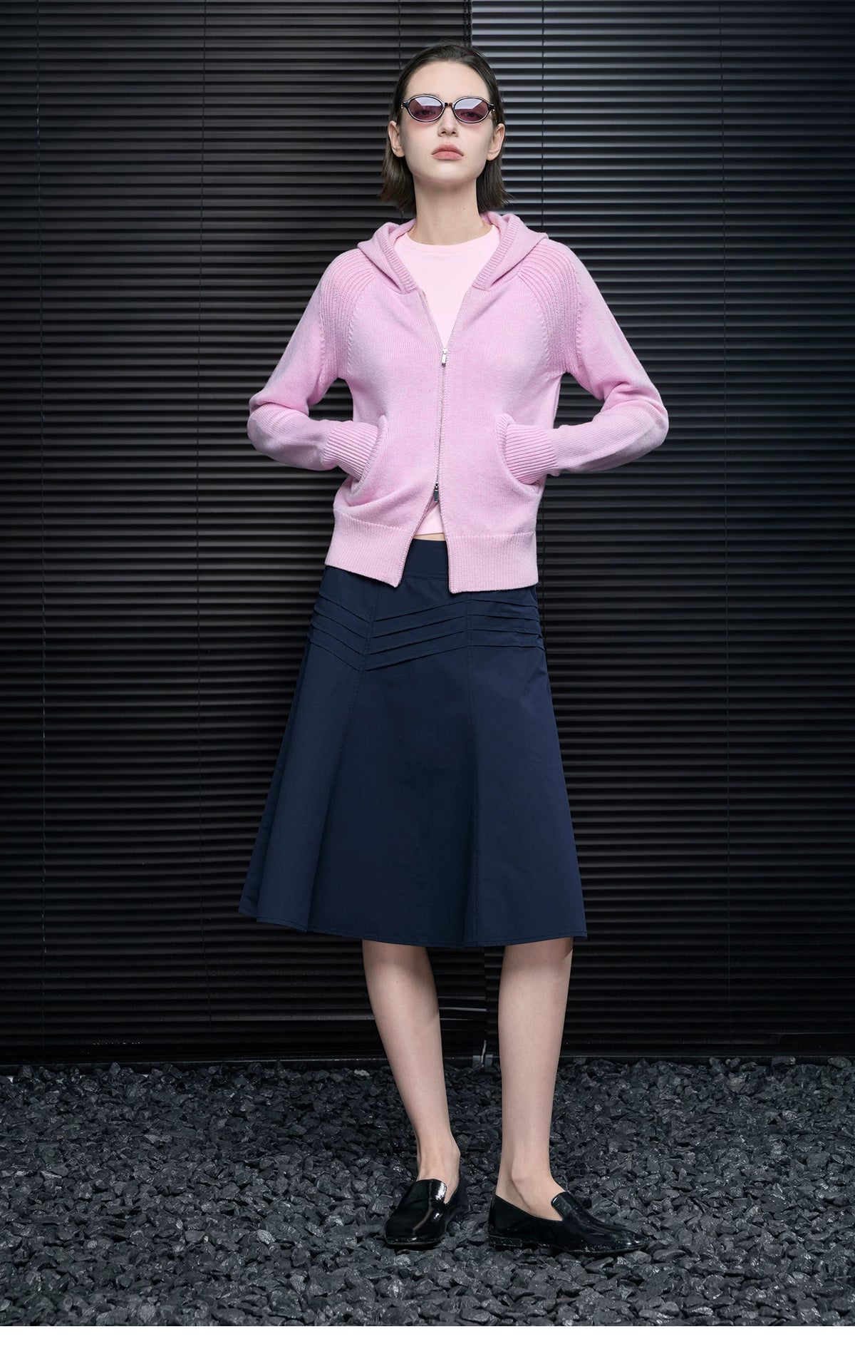 Full-length look of Pastel Pink wool-blend zip hoodie with navy pleated midi skirt and black loafers