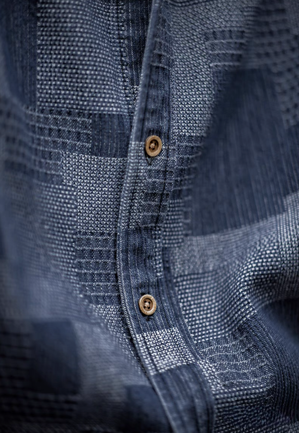 Close-up of Denim Blue patchwork indigo shirt showing intricate woven texture, stitching details, and button placket