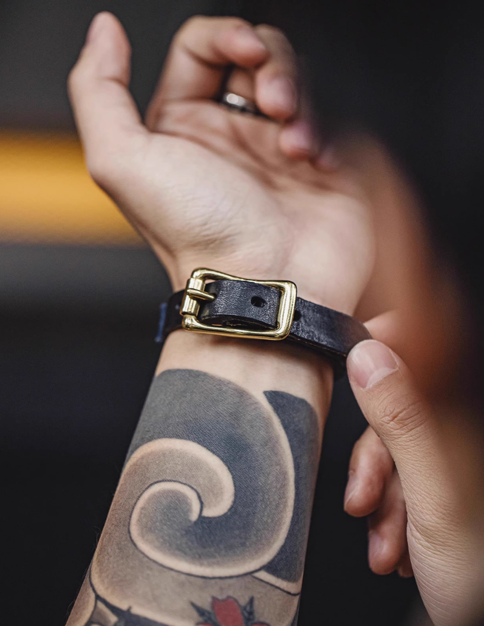 Patchwork leather bracelet worn on wrist showing black leather strap and brass buckle detail