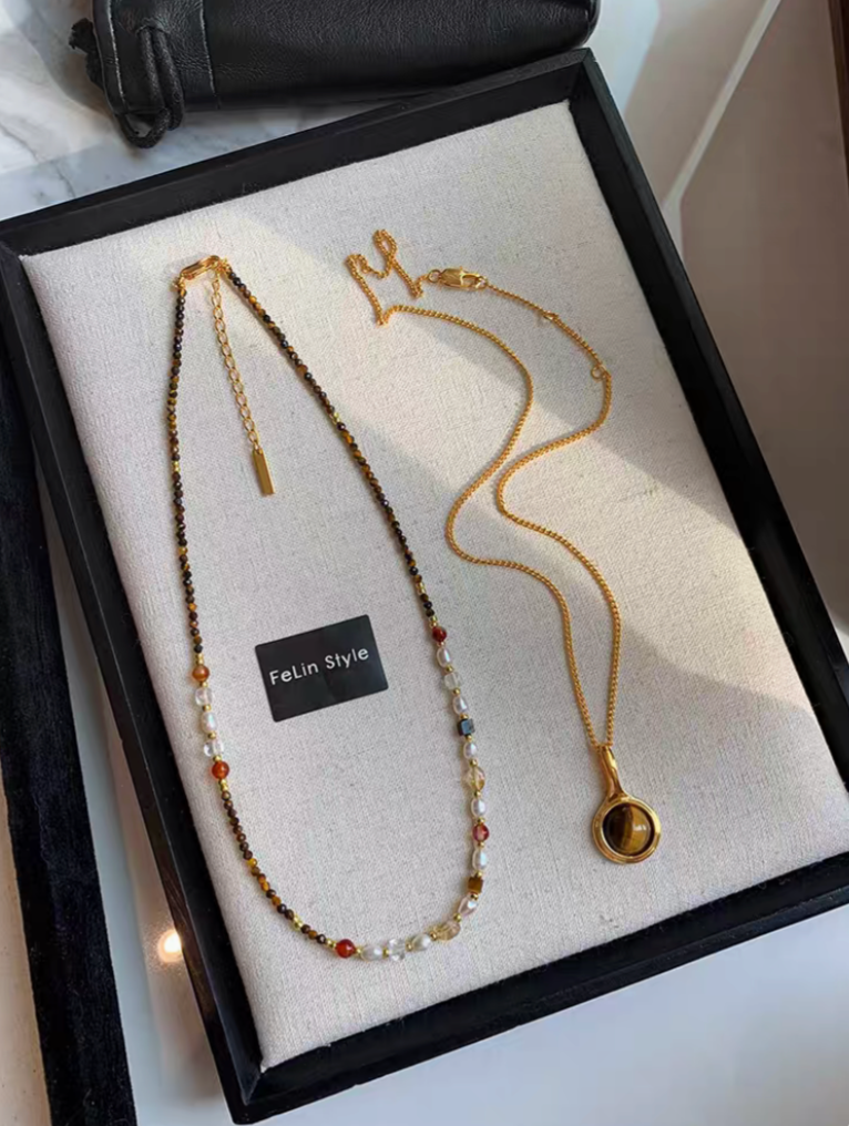 Classic pearl and tiger eye two-necklace set featuring multicolor beaded choker with freshwater pearls and gold tiger eye pendant necklace displayed on tray