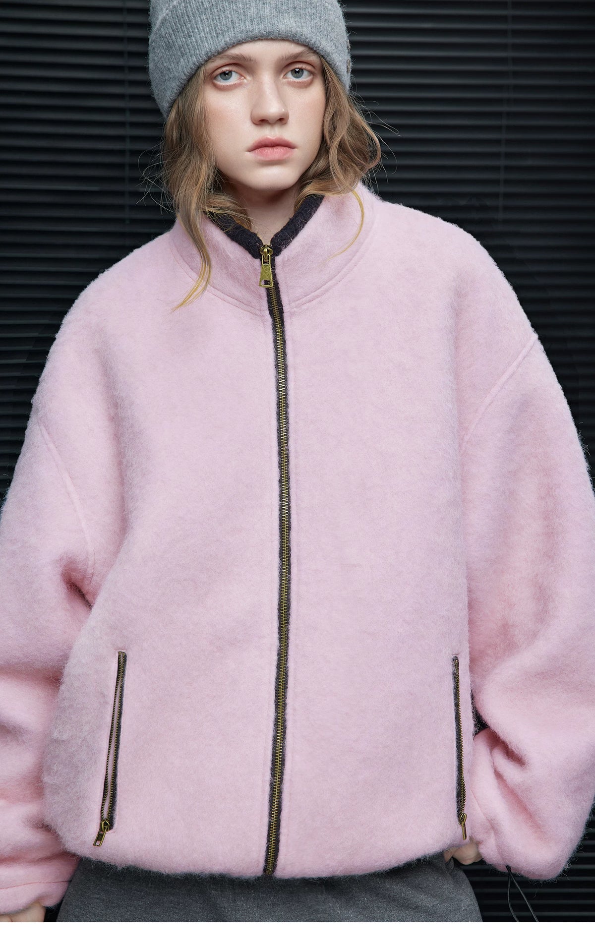 Close-up of a Pink fuzzy zip jacket showing brass-tone zippers and charcoal contrast binding