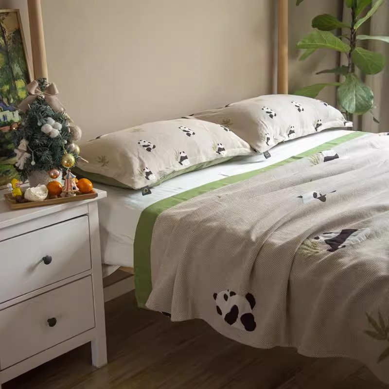 Playful Pals Cotton Gauze Quilted Blanket Panda styled on a bedroom bed with panda pattern bedding and green trim