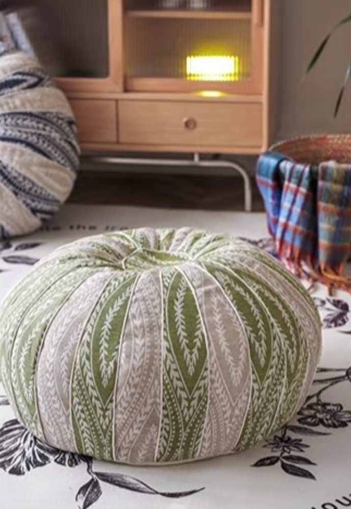 Green pumpkin round floor cushion placed on a floral rug in a living room setting