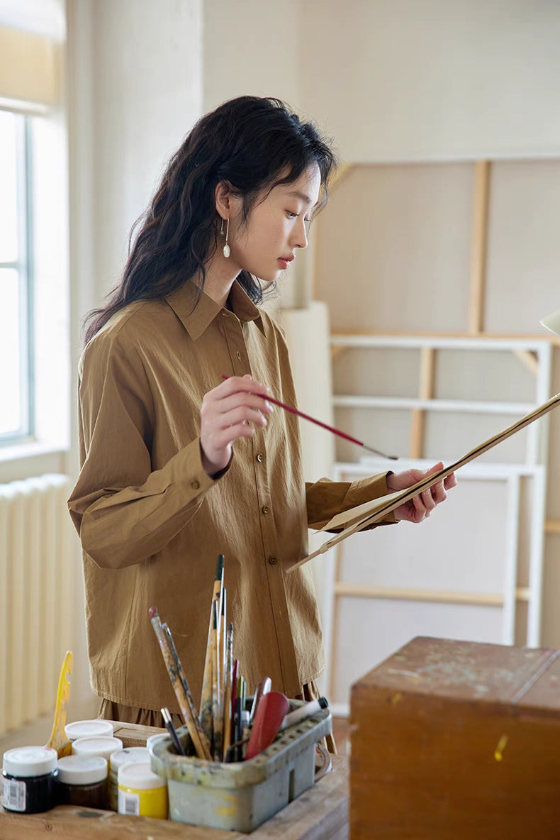 Model wearing Earth Tone long-sleeve cotton blouse and midi skirt set while painting, highlighting soft structure and creative lifestyle use