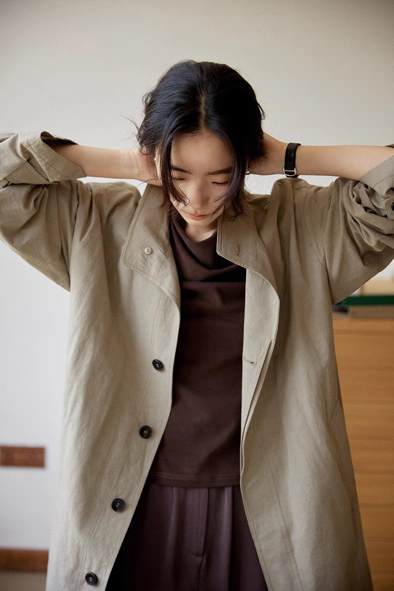 Woman wearing the gray Relaxed Cotton-Linen Trench in an open front close-up view, showcasing horn button closure, relaxed silhouette, and lightweight cotton-linen texture