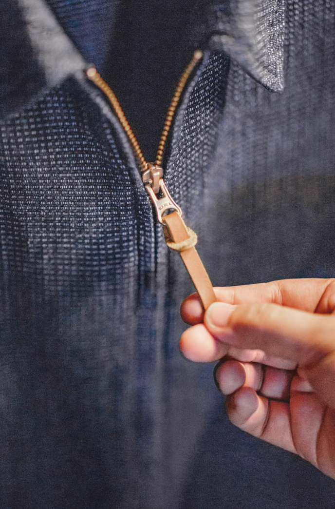 Close-up of zipper with leather pull tab on denim coach jacket