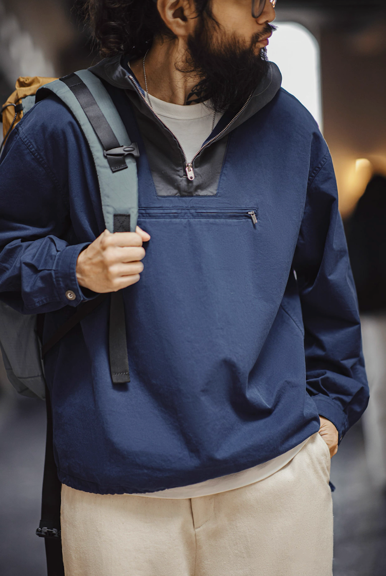 Model wearing navy two-tone anorak with backpack, urban street style.