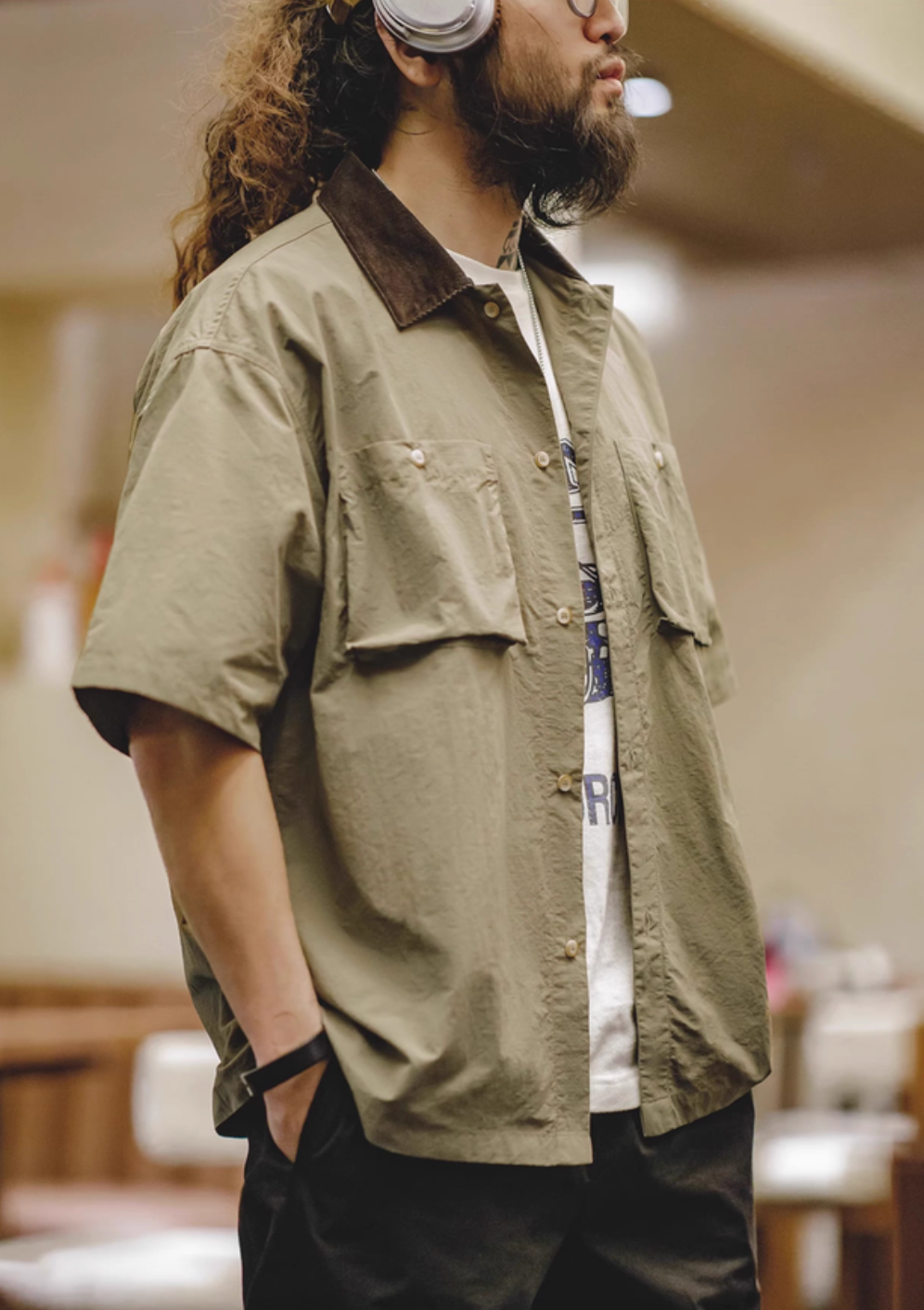 Side view of man wearing khaki green retro waterproof utility shirt highlighting relaxed fit and dual chest pockets